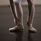 Dancer bending over to fix her pointe shoes