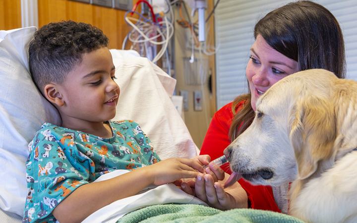 Kizzy, a child life specialist, and Ralph use a syringe to show a patient how to take a medication.