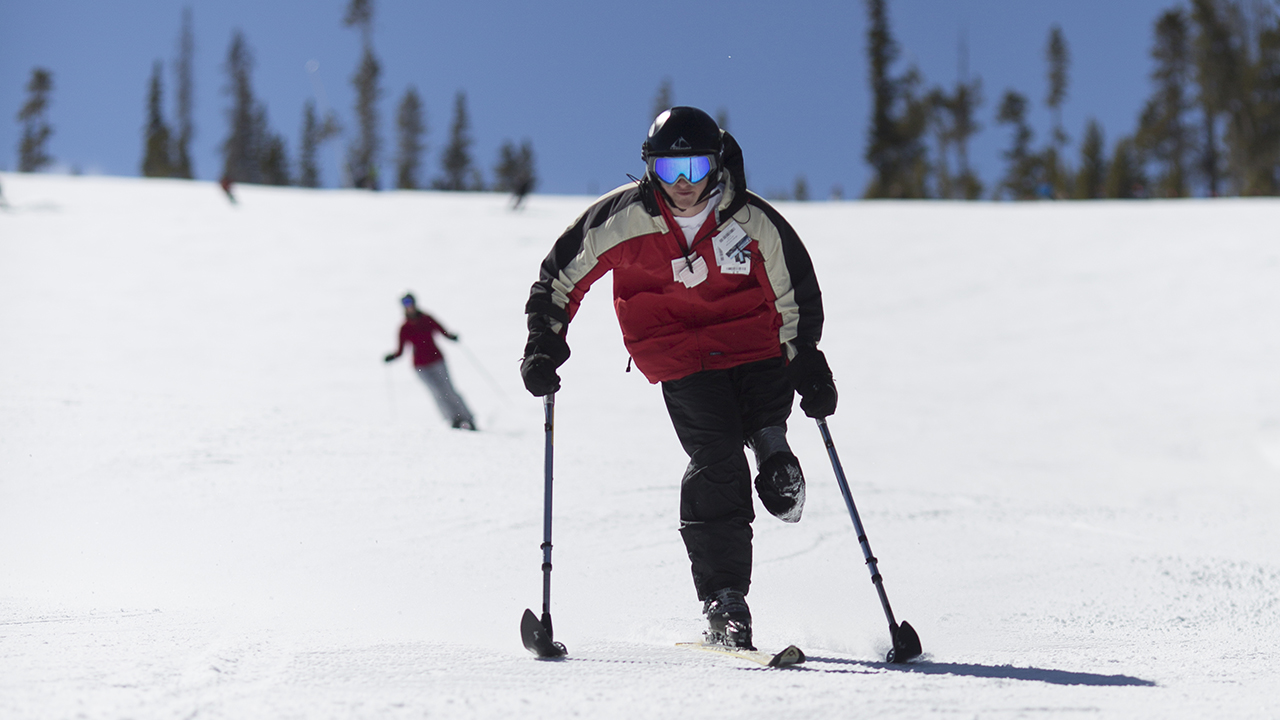 A teenager in the ARCH Program skis down the mountain using adaptive ski equipment.