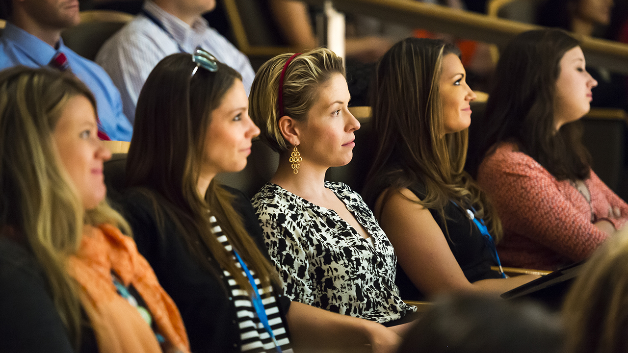 Healthcare professionals listen to a lecture in an auditorium.