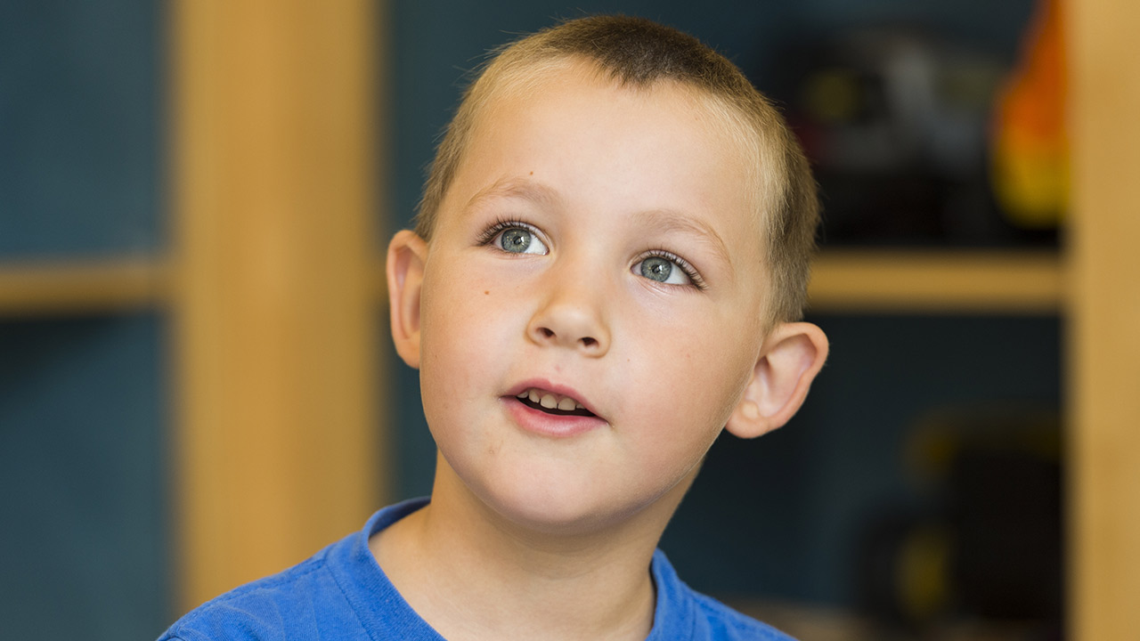 Young boy in blue shirt looks up.