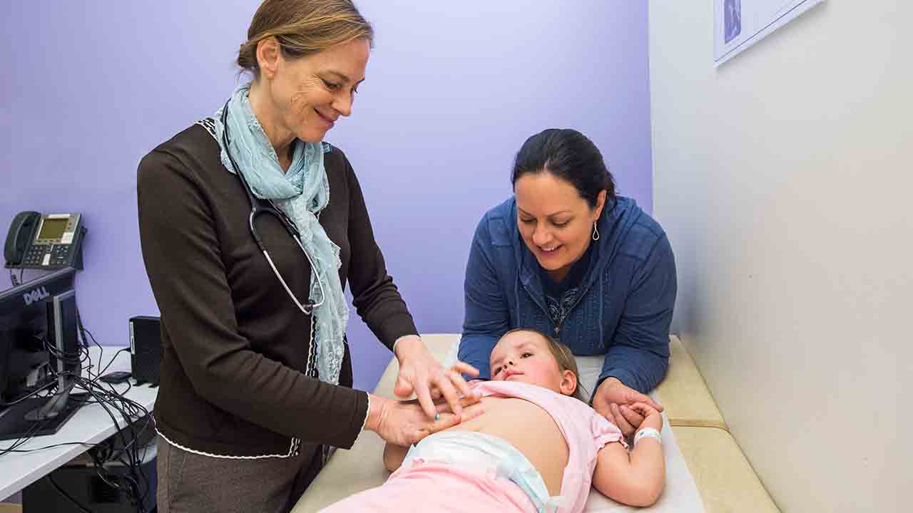 Dr. Cara Mack examines a girl's stomach